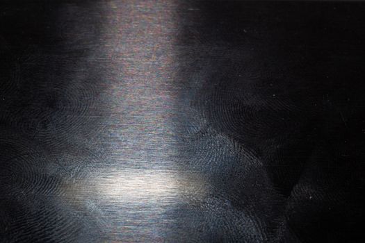 oily gloss black steel surface with many fingerprints - closeup with selective focus.