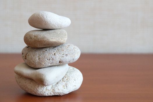 pyramid of round natural stones on a wooden background as a symbol of harmony and balance