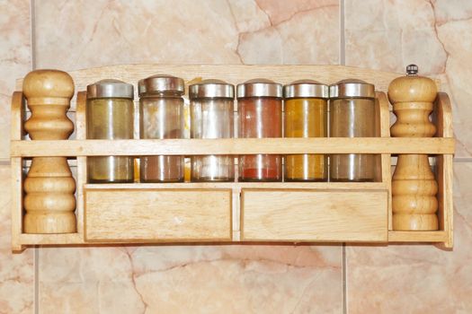 glass jars with spices on a wooden stand on the wall