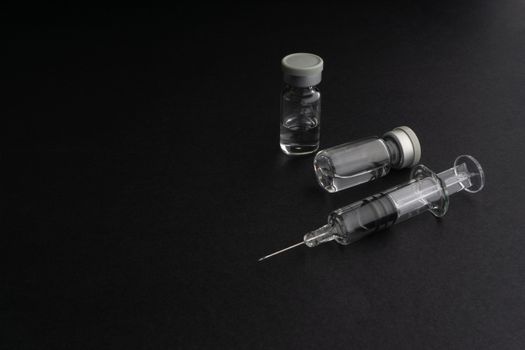 Closeup syringe and vials on black background. Healthcare dan Copy Space concept