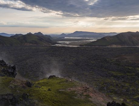 Lava field landscape in Landmannalaugar with and geothermal fumarole, river delta and Rhyolit mountain at Sunrise in Fjallabak Nature Reserve, Highlands Iceland.