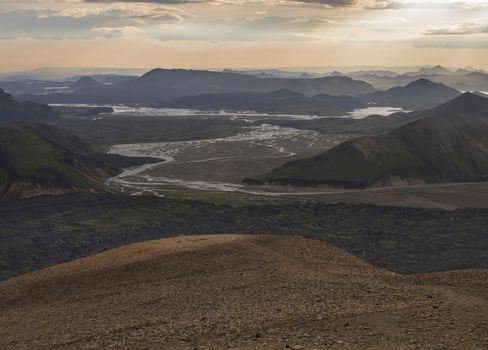 Colorful Rhyolit mountain panorma with view on Landmannalaugar campsite at river delta. Sunrise in Fjallabak Nature Reserve, Highlands Iceland.