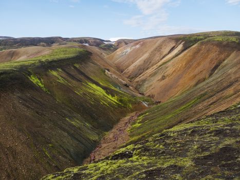 Colorful Rhyolit mountain panorma with multicolored volcanos and small creek in Landmannalaugar area of Fjallabak Nature Reserve in Highlands region of Iceland.