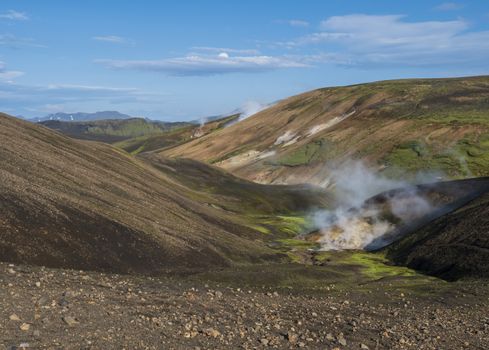 Landmannalaugar colorful Rhyolit mountains with steam from hot spring on famous Laugavegur trek. Fjallabak Nature Reserve in Highlands of Iceland, summer blue sky