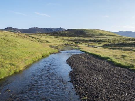 Volcanic hills, lush grass and blue river next to camping site on Alftavatn lake. Summer sunny day, landscape of the Fjallabak Nature Reserve in Highlands Iceland part of Laugavegur hiking trail