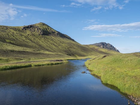 Beautiful green hills, lush grass and blue river next to camping site on Alftavatn lake. Summer sunny day, landscape of the Fjallabak Nature Reserve in Highlands Iceland part of Laugavegur hiking trail