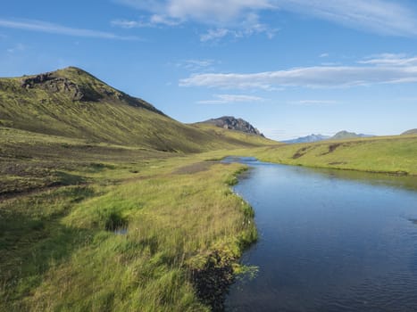 Beautiful green hills, lush grass and blue river next to camping site on Alftavatn lake. Summer sunny day, landscape of the Fjallabak Nature Reserve in Highlands Iceland part of Laugavegur hiking trail