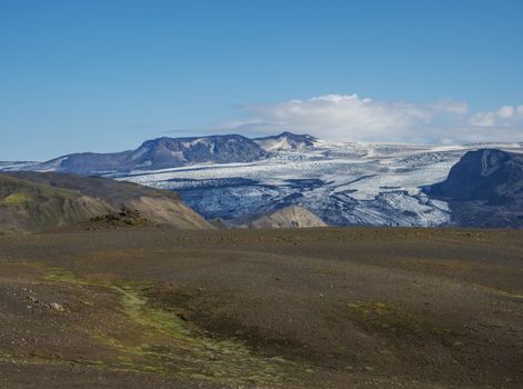 Icelandic landscape with eyjafjallajokull glacier tongue, Markarfljot river and green hills. Fjallabak Nature Reserve, Iceland. Summer blue sky.