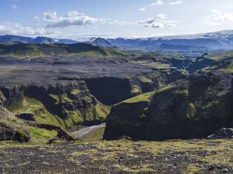 View on majestic Markarfljotsgljufur Canyon gorge, river and Tindfjallajokull glacier tongue and green hills. Fjallabak Nature Reserve, Iceland. Summer blue sky, clouds