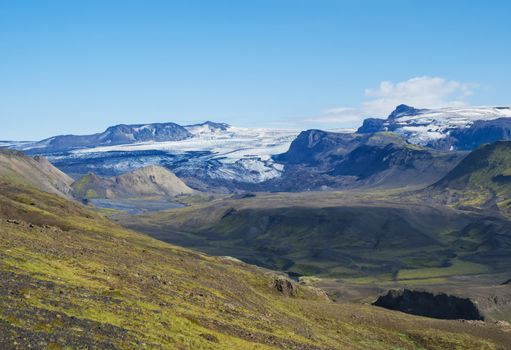 Icelandic landscape with eyjafjallajokull glacier tongue, Markarfljot river and green hills. Fjallabak Nature Reserve, Iceland. Summer blue sky.
