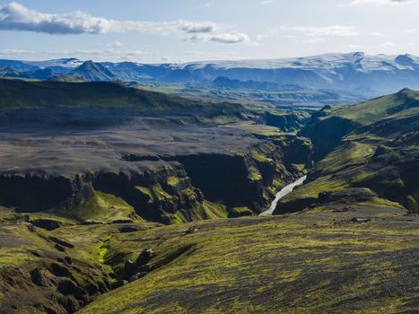 View on majestic Markarfljotsgljufur Canyon gorge, river and Tindfjallajokull glacier tongue and green hills. Fjallabak Nature Reserve, Iceland. Summer blue sky, clouds