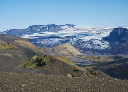 Icelandic landscape with eyjafjallajokull glacier tongue, Markarfljot river and green hills. Fjallabak Nature Reserve, Iceland. Summer blue sky.