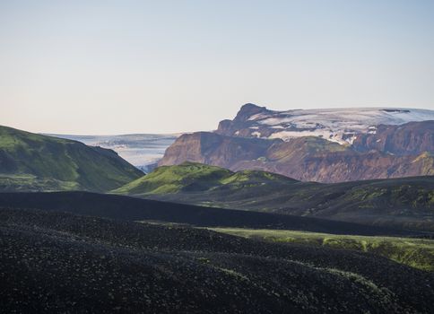 Sunrise at Botnar campsite at Iceland on Laugavegur hiking trail, green valley in volcanic landscape with view on Myrdalsjokull glacier. Early morning pink light.