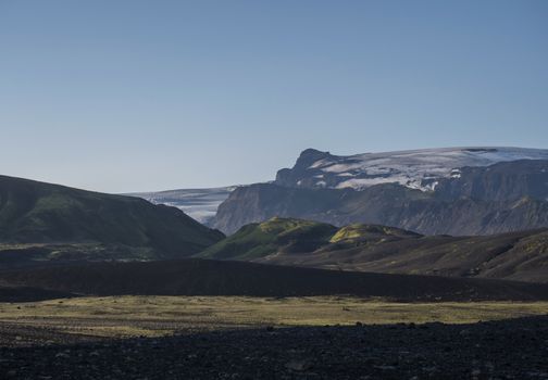 Sunrise view on Myrdalsjokull glacier. from Botnar campsite at Iceland on Laugavegur hiking trail, green valley in volcanic landscape with Early morning pink light.