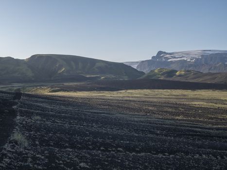 Sunrise view on Myrdalsjokull glacier at Iceland from Laugavegur hiking trail, green valley in volcanic landscape with Early morning pink light.