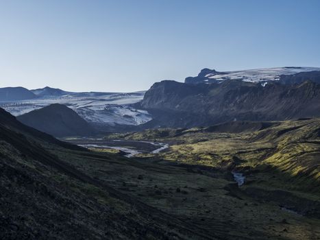 Icelandic landscape with eyjafjallajokull glacier tongue, Markarfljot river and green hills. Fjallabak Nature Reserve, Iceland. Summer blue sky.