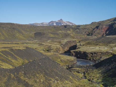 Icelandic landscape with blue Markarfljot river canyon, green hills and Tindfjallajokull glacier mountain peak. Fjallabak Nature Reserve, Iceland. Summer blue sky.