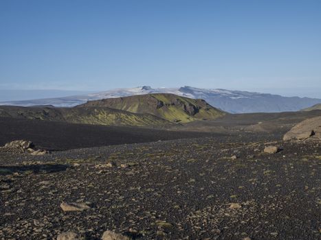 Icelandic landscape with eyjafjallajokull glacier tongue, blue river stream and green hills. Fjallabak Nature Reserve, Iceland. Summer blue sky.