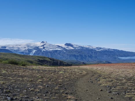 Icelandic landscape with red grass, birch bush, green hills and eyjafjallajokull volcano glacier. Laugavegur hiking trail. Fjallabak Nature Reserve, Iceland. Summer blue sky.