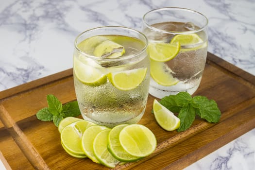 Cold Drink from Lemon cut into pieces in water glass on wood cup