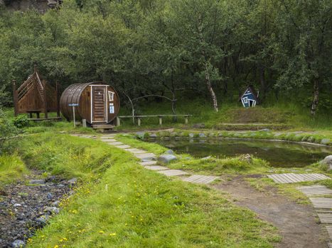 Geothermal hot pool with sauna at the Husadalur Camp in the birch forest in Thorsmork valley, Iceland.