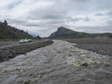 ICELAND, THORSMORK, August 3, 2019: view on glacier wild river Krossa and green sharp volanic hills from footbridge border of Thorsmork and Godaland.