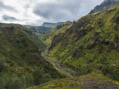 Landscape of Godland and thorsmork with rugged green moss covered rocks and hills, bending river canyon, Iceland, Fimmvorduhals trek. Summer cloudy day.