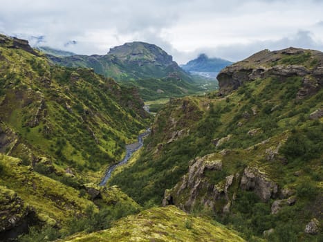 Landscape of Godland and thorsmork with rugged green moss covered rocks and hills, bending river canyon, Iceland, Fimmvorduhals trek. Summer cloudy day.