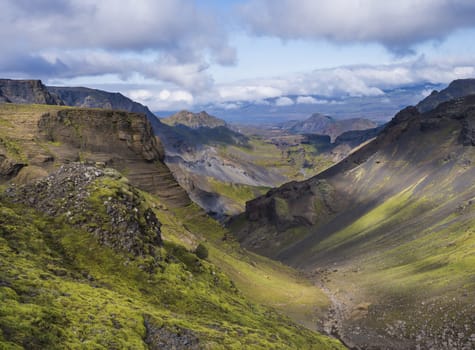 Landscape of Godland and thorsmork with rugged green moss covered rocks and hills, bending river canyon, Iceland, Fimmvorduhals hiking trail. Summer blue sky white clouds.