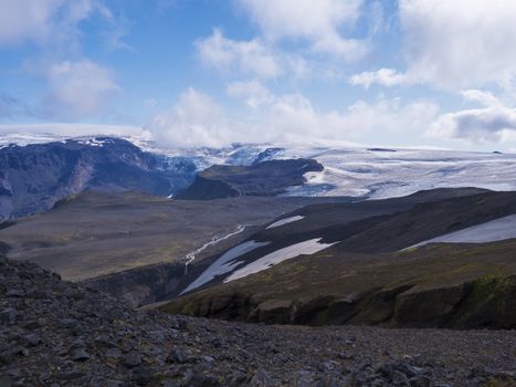 View over a landscape of Godland and thorsmork with the Eyjafjallajokull glacier and volcano, lava formations, snow, ice and green moss. Iceland, Fimmvorduhals hiking trek. Summer cloudy day.