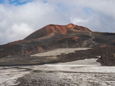Red and black volcanic Iceland landscape at Fimmvorduhals hiking trail with glacier volcano lava field, snow and magni and mudi hill, createed by eruption of Eyjafjallajokull in 2010 which affected air traffic in the whole Europe. Summer blue sky.