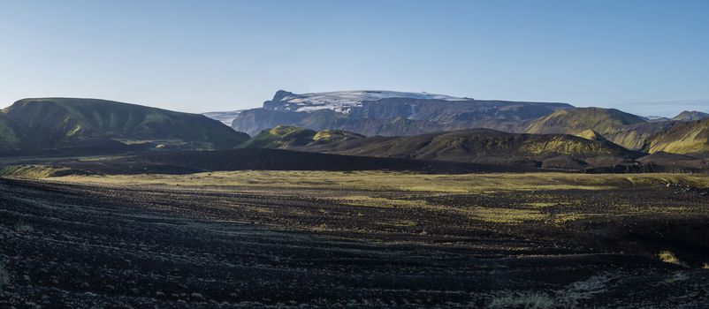 Panoramic sunrise view on Myrdalsjokull glacier. from Botnar campsite at Iceland on Laugavegur hiking trail, green valley in volcanic landscape with Early morning pink light.