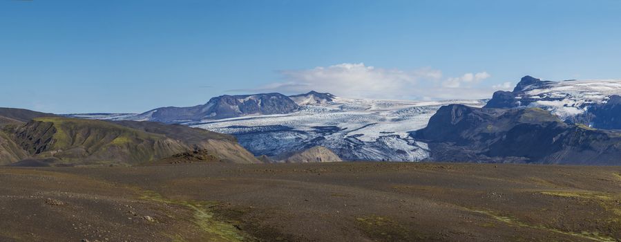 Icelandic landscape with eyjafjallajokull glacier tongue, Markarfljot river and green hills. Fjallabak Nature Reserve, Iceland. Summer blue sky.