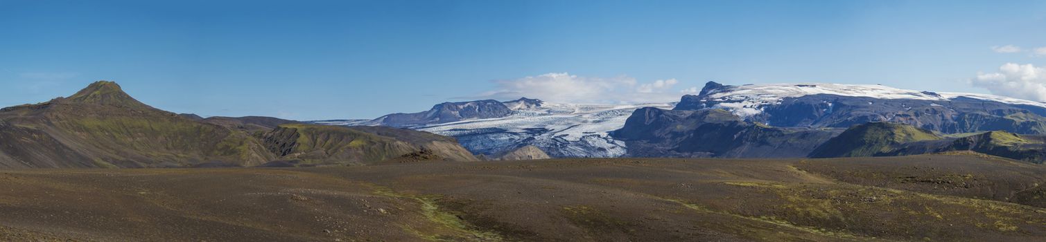 Icelandic landscape with eyjafjallajokull glacier tongue, Markarfljot river and green hills. Fjallabak Nature Reserve, Iceland. Summer blue sky.