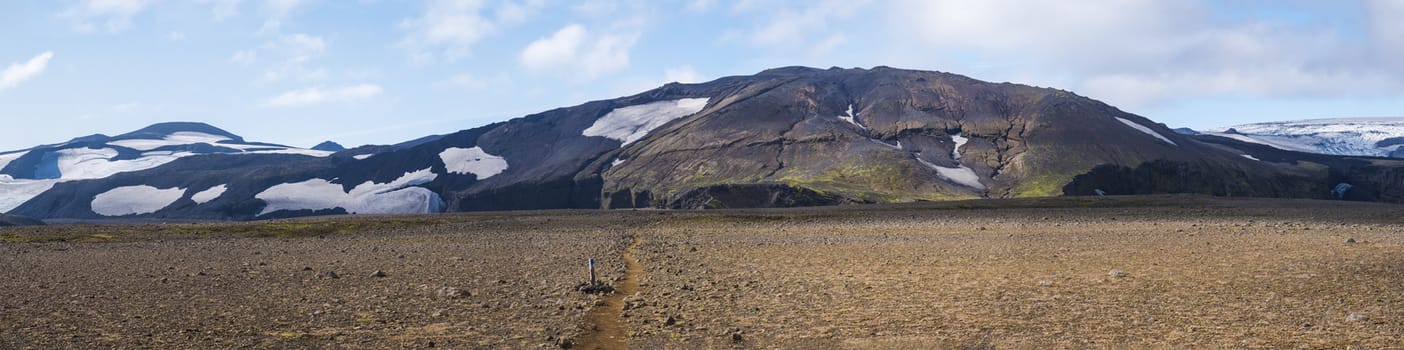 Panoramic Icelandic lava desert landscape with top of Eyjafjallajokull glacier and volcano, partialy covered in clouds. Iceland, Fimmvorduhals hiking trail. Summer sunny day