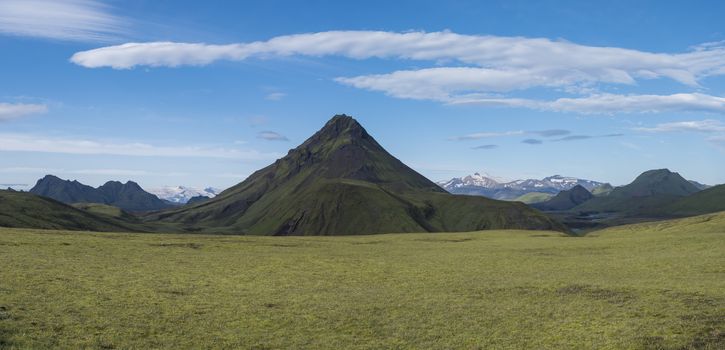 Panoramic volcanic landscape of green Stora-sula mountain with Tindfjallajokull glacier, lush moss and blue creek water on Laugavegur trek in area of Fjallabak Nature Reserve, Iceland.