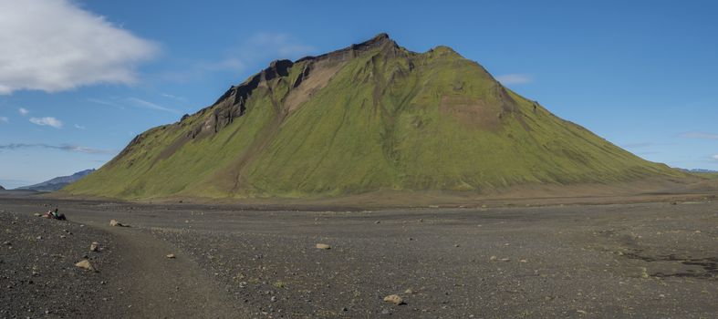 Panoramic view on green Hattafell mountain in Volcanic landscape witj resting tourist hiker. Laugavegur trek in area of Fjallabak Nature Reserve in Highlands region of Iceland..