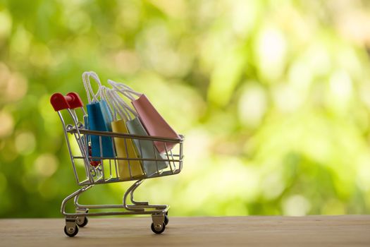 Online shopping, e-commerce concept: Paper shopping bags in a trolley or shopping cart  in the natural green background. purchase of products on internet can purchase goods from foreign countries