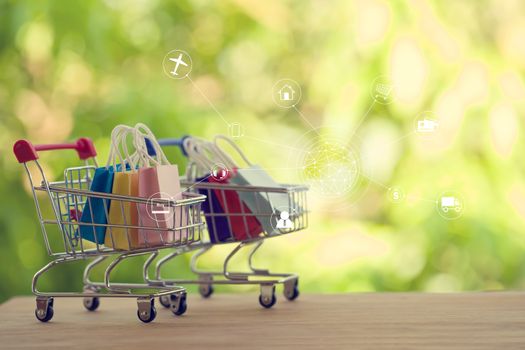 e-commerce concept: Paper shopping bags in a trolley or shopping cart with an icon linking business plans in the natural green background. International freight or shipping service for online shopping