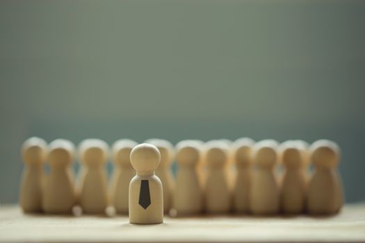 Successful business team leader concept: Wooden figures of man and people standing out from the crowd. depicts ability of individual to influence and lead followers or other members of organization.