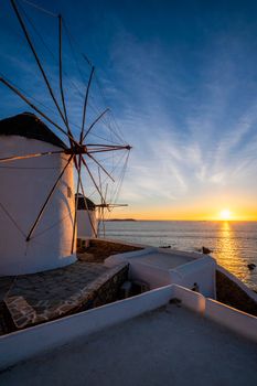 Scenic view of famous Mykonos Chora town windmills. Traditional greek windmills on Mykonos island illuminated in the evening, Cyclades, Greece. Walking with steadycam.