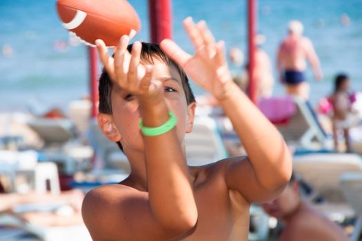 The boy plays with a ball a beach