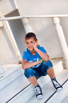 The carefree boy dreams sitting on a porch