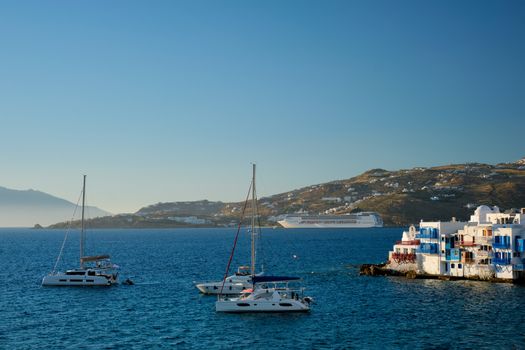 Sunset in Mykonos island, Greece with yachts in the harbor and colorful waterfront houses of Little Venice romantic spot on sunset and cruise ship. Mykonos townd, Greece