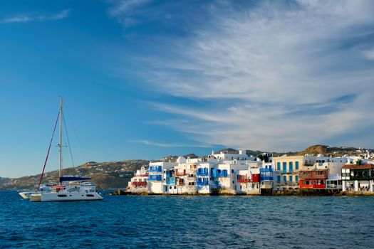 Sunset in Mykonos island, Greece with yachts in the harbor and colorful waterfront houses of Little Venice romantic spot on sunset and cruise ship. Mykonos townd, Greece