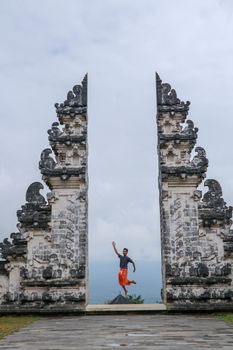 Bali, Indonesia. Young taveler man jumping with energy and happiness in the gate of heaven. Lempuyang temple.