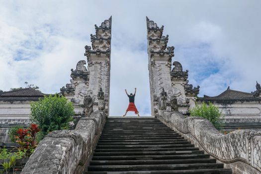 Bali, Indonesia. Young taveler man jumping with energy and happiness in the gate of heaven. Lempuyang temple.