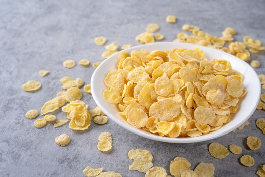 Corn flakes bowl sweeties with milk on gray cement background, close up, fresh and healthy breakbast design concept.