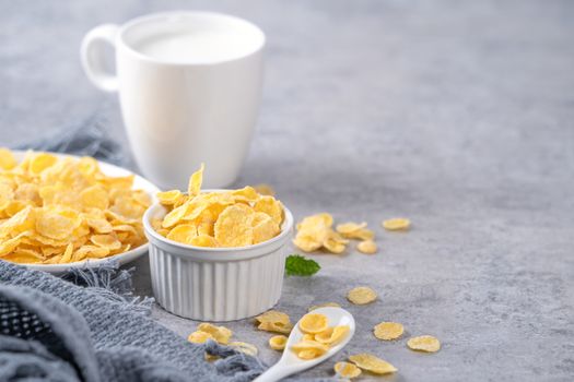 Corn flakes bowl sweeties with milk on gray cement background, close up, fresh and healthy breakbast design concept.