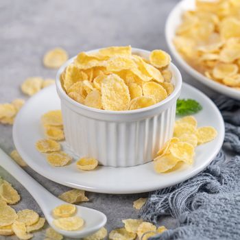 Corn flakes bowl sweeties with milk on gray cement background, close up, fresh and healthy breakbast design concept.